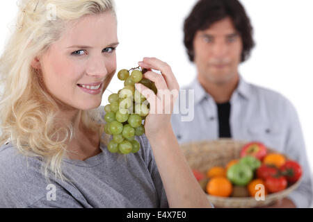 Bella bionda sorridente mangiare uva Foto Stock