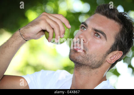 Uomo di mangiare un apple sotto un albero Foto Stock