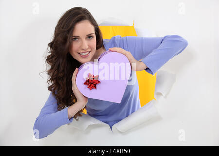 Brunette holding heart-shaped box Foto Stock