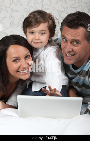 Posa di famiglia con il computer portatile Foto Stock
