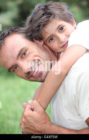 Padre dando figlio piggy back all'aperto Foto Stock