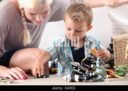 La madre e il bambino che gioca con automobili giocattolo Foto Stock