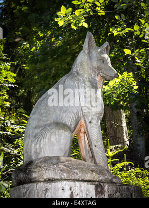 Una scultura in legno di un fox (o forse lupo), scolpita da un tronco di albero, lungo un sentiero natura in Svizzera Foto Stock