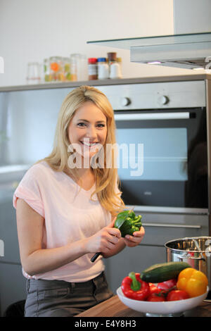 Donna felice cucinare un pasto in cucina Foto Stock