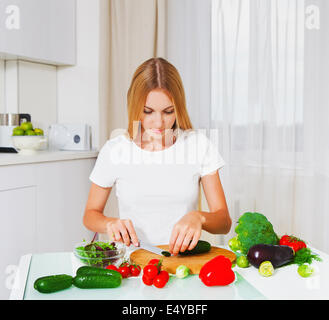 Giovane donna tagliare le verdure Foto Stock