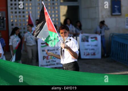 Betlemme. 17 Luglio, 2014. Un membro di scout palestinese sventola una bandiera nazionale durante una manifestazione di protesta contro la violenza verso i bambini palestinesi nella striscia di Gaza nel contesto del conflitto israelo-palestinese in Cisgiordania città di Betlemme il 17 luglio 2014. Sanità palestinese hanno detto i funzionari che in totale, 234 palestinesi sono stati uccisi e più di 1700 altri feriti dal luglio 8. Credito: Luay Sababa/Xinhua/Alamy Live News Foto Stock