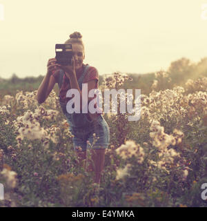 Fotografo ragazza tenendo la foto in campo Foto Stock