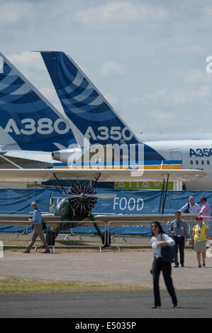 Aerodromo di Farnborough Hampshire, Regno Unito. 17 luglio 2014. Il salone aerospaziale internazionale è il Regno Unito il più grande evento nel settore aerospaziale e della difesa, del calendario che si tiene ogni due anni. Fornire opportunità di affari per l'industria aerospaziale globale si apre anche al pubblico il 19-20 luglio, quest'anno celebra i suoi cento anni di storia dell'aviazione. Aeromobili partecipanti raggiungono un nuovo alto per Farnborough International Airshow di quest'anno, sponsorizzato dal gruppo di Airbus. Un biplano e aeromobili Airbus il giorno 4 del Trade Show. Credito: Malcolm Park editoriale/Alamy Live News. Foto Stock