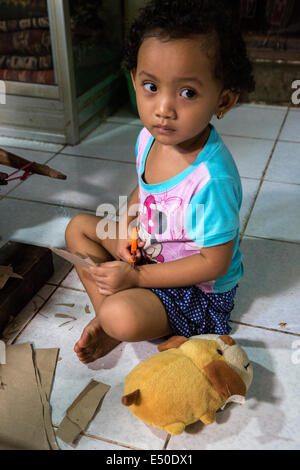 Bali, Indonesia. Piccola ragazza Balinese e i suoi animali impagliati. Villaggio di Tenganan. Foto Stock