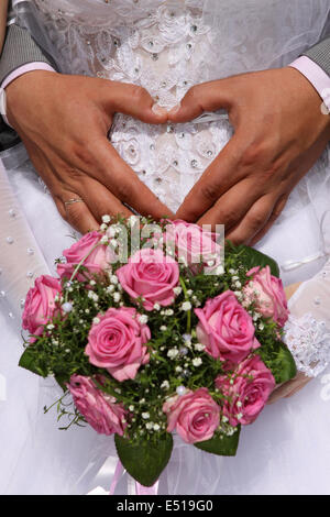 Le mani della sposa e lo sposo in una forma di cuore Foto Stock