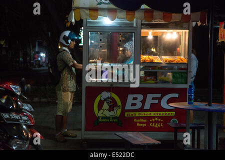 Jimbaran, Bali, Indonesia. Giovane uomo a Bali il pollo fritto Stand, di notte. Foto Stock