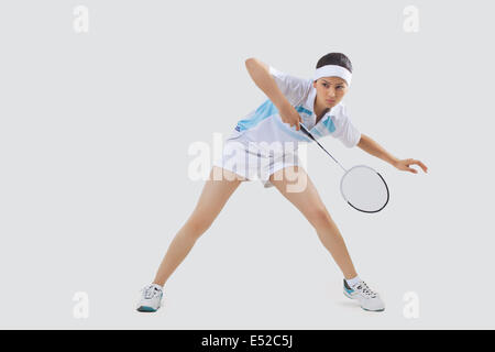 Per tutta la lunghezza della giovane donna giocando badminton isolate su uno sfondo grigio Foto Stock