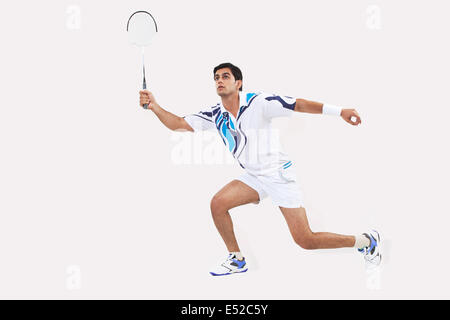 Giovane uomo in sports wear riproduzione di badminton contro uno sfondo bianco Foto Stock