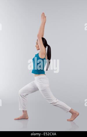 Colpo di profilo di giovane donna bracci di estensione verso l'alto isolato su sfondo grigio Foto Stock