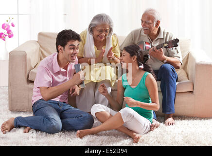 Nonno suonare la chitarra con la nonna e nipoti cantando Foto Stock
