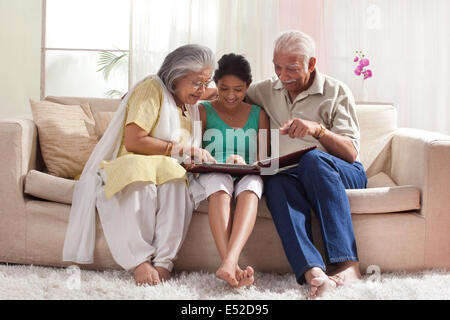 La nipote guardando una foto di un album con i suoi nonni Foto Stock