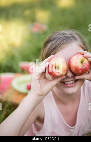 Una ragazza con due mele davanti agli occhi Foto Stock