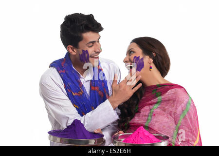 L'uomo applicando holi colore sul viso di donna Foto Stock