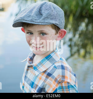Un giovane ragazzo che indossa una maglietta controllato il panno e il cappuccio con un orlo di grandi dimensioni in piedi su un argine. Foto Stock