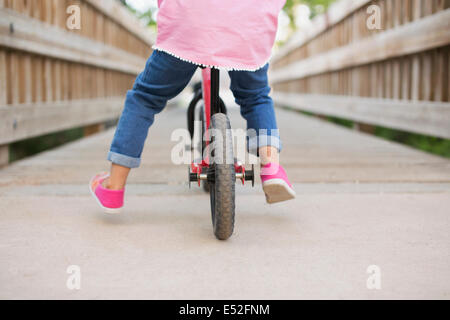 Un bambino in sella ad una bicicletta su una passerella. Foto Stock