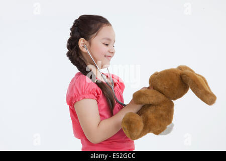 Bambina riproduzione medico con un coniglio giocattolo Foto Stock