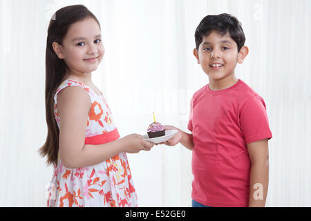Ritratto di un ragazzo e una ragazza tenendo un cupcake Foto Stock