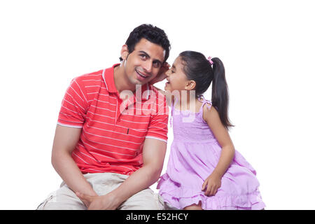 Felice figlia whispering in padre l orecchio su sfondo bianco Foto Stock