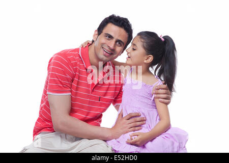 Figlia whispering in padre l orecchio contro uno sfondo bianco Foto Stock