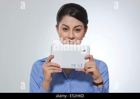 Ritratto di sorridere imprenditrice azienda digitale compressa contro uno sfondo grigio Foto Stock