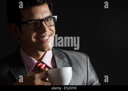 Ritratto di happy businessman con tazza di caffè su sfondo nero Foto Stock