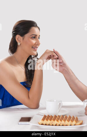 Immagine ritagliata dell uomo donna tenendo la mano mentre avente caffè contro uno sfondo bianco Foto Stock
