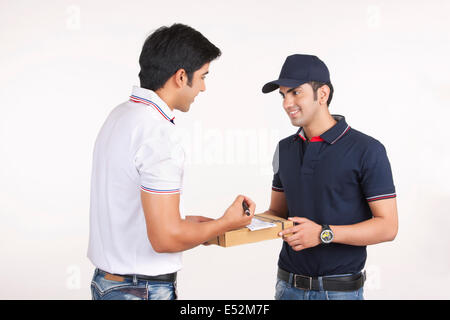 Consegna sorridente uomo pacchetto di consegna al cliente contro uno sfondo bianco Foto Stock