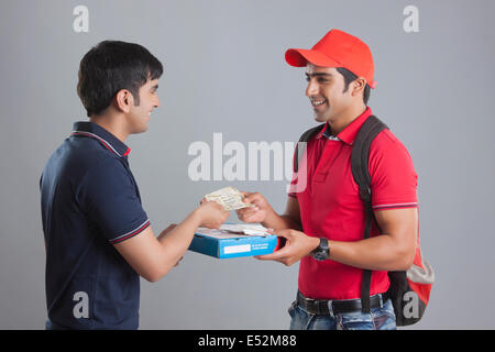 Sorridente uomo consegna pizza consegna al cliente contro uno sfondo grigio Foto Stock