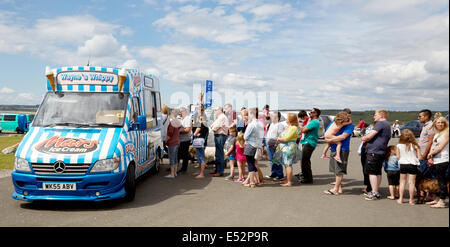 Nella coda del paziente per vacanza in attesa di gelato da un furgone parcheggiato in un mare di Welsh parcheggio auto in estate Foto Stock