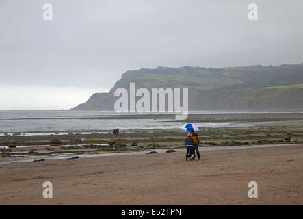 Robin Hood's Bay vicino a Whitby, nello Yorkshire, Regno Unito. Il 18 luglio 2014. Mentre gran parte del Regno Unito si crogiola al sole e temperature record, sulla costa dello Yorkshire ci sono cieli grigi, piovigginare e una gelida brezza. Credito: Julia Gavin/Alamy Live News Foto Stock