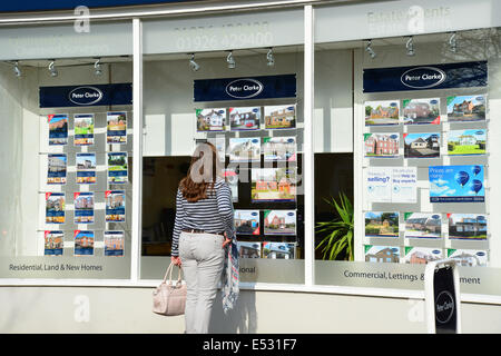 Donna che guarda in agenti immobiliari finestra, Euston posto, Royal Leamington Spa Warwickshire, Inghilterra, Regno Unito Foto Stock