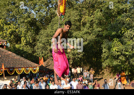 La devota Hindu trafitto da ganci acuti e sollevato dal suolo su una impalcatura utilizzando corde. Konkan, Maharashtra, India Foto Stock