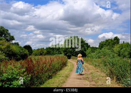 Viste intorno al Mulino di Flatford area che sono stati resi famosi da dipinti di John Constable - Donna che cammina verso il basso il percorso del paese Foto Stock