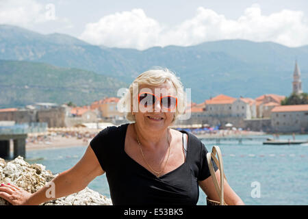 Ritratto di anziana signora e la città vecchia vicino al mare in Budva Montenegro, come sfondo. Foto Stock