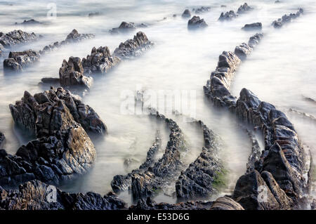 Rocce sulla spiaggia con una lunga esposizione Foto Stock