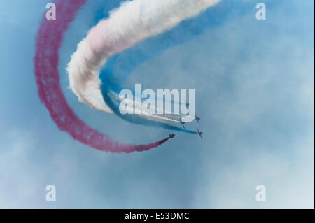 Aerodromo di Farnborough Hampshire, Regno Unito. Il 18 luglio 2014. Il salone aerospaziale internazionale è il Regno Unito il più grande evento nel settore aerospaziale e della difesa, del calendario che si tiene ogni due anni. Rosso patriottica, bianco e blu fumo dalla RAF frecce rosse aerobatic team display come aeromobile passano attraverso fumo esistenti sentieri. Credito: Malcolm Park editoriale/Alamy Live News. Foto Stock