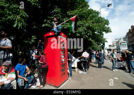 Londra REGNO UNITO. Il 19 luglio 2014. Un manifestante si siede sulla parte superiore di una casella telefono con una bandiera della Palestina durante una manifestazione di protesta al di fuori dell'ambasciata Israeliana a Londra per mostrare il loro sostegno per il popolo palestinese e contro israeliani in corso gli attacchi militari nella Striscia di Gaza: Credito amer ghazzal/Alamy Live News Foto Stock