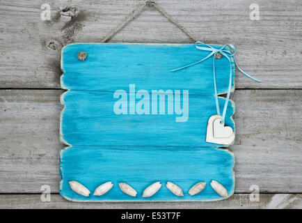 Blank teal cartello blu con conchiglie e cuori appesi rustico sfondo di legno Foto Stock