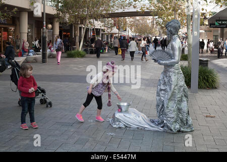 Una ragazzina di mettere il denaro in una teglia per una strada performer di Perth è Murray Street Mall. Western Australia. Foto Stock