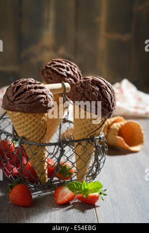 Cioccolato crams di ghiaccio con le fragole e i coni di vuoto in background Foto Stock