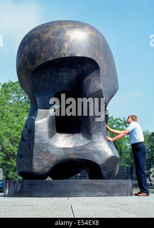 Un uomo riceve uno sguardo più da vicino a "Energia nucleare", un astratto scultura in bronzo di Henry Moore sull'Università di Chicago campus a Chicago, Illinois, Stati Uniti d'America. Foto Stock