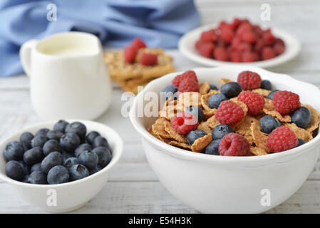 Intero in scaglie di grana nella ciotola con frutti di bosco freschi su sfondo chiaro Foto Stock