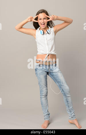 Canto ragazza adolescente ballare per tutta la lunghezza su sfondo grigio Foto Stock
