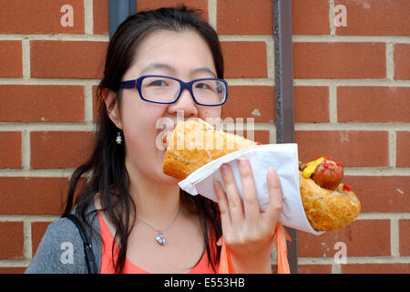 Giovane donna cinese mangia un enorme hot dog a Southsea food fair festival 2014 England Regno Unito Foto Stock