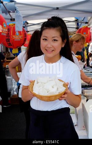 Sorridente ragazza cinese con cesto di cracker ai gamberi a Southsea food fair festival 2014 England Regno Unito Foto Stock